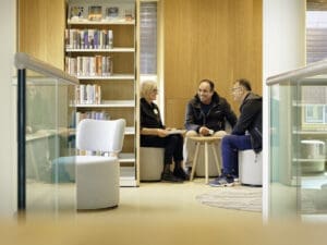 In een rustig hoekje in de bibliotheek geeft een dame uitleg aan twee heren.