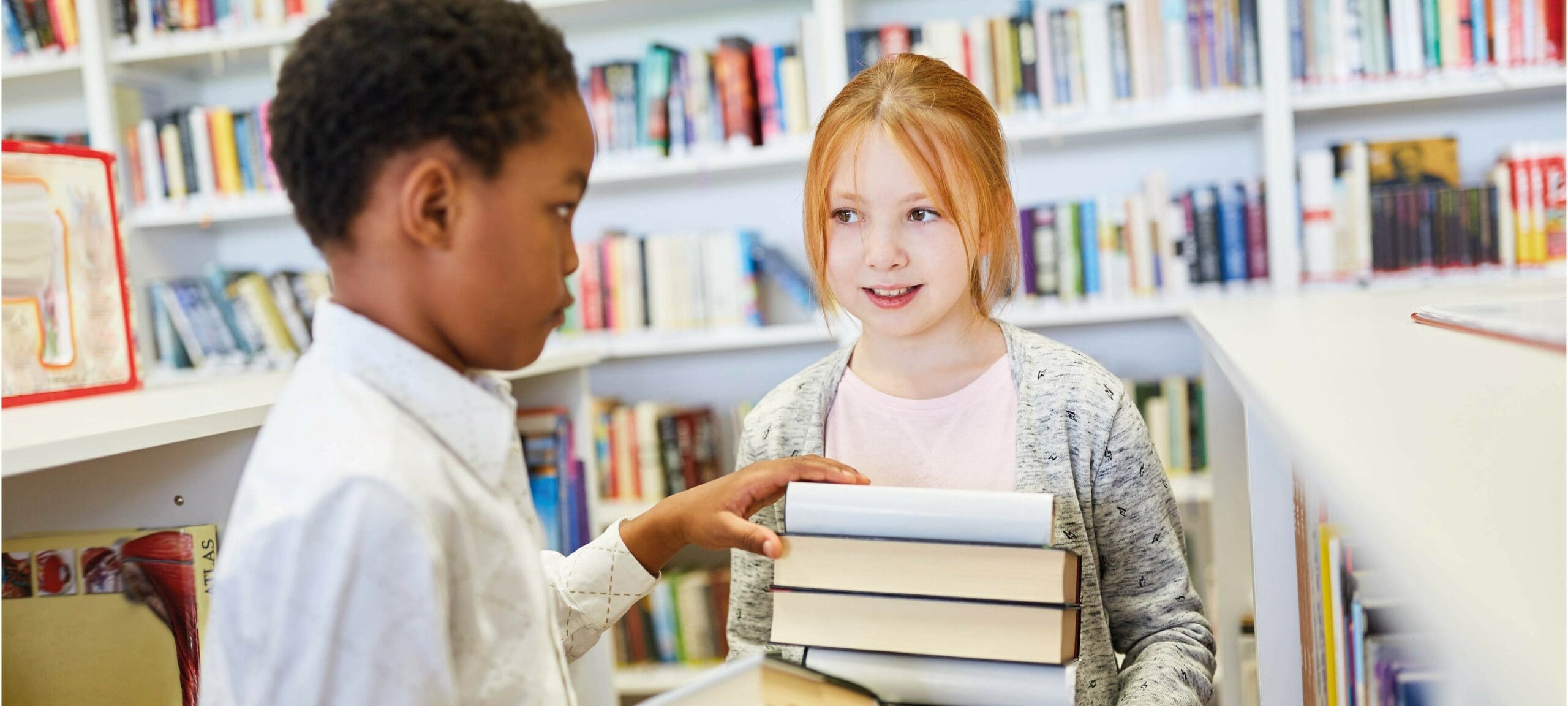 Twee jonge kinderen met een stapel boeken in de hand