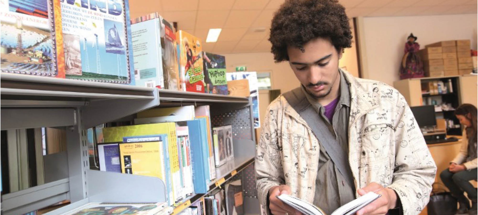 man loopt langs boeken