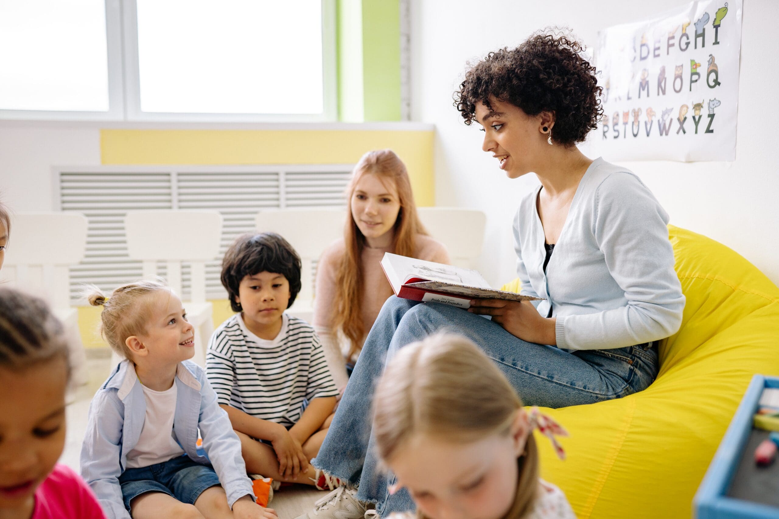 Een vrouwelijke docent leest voor aan jonge kinderen
