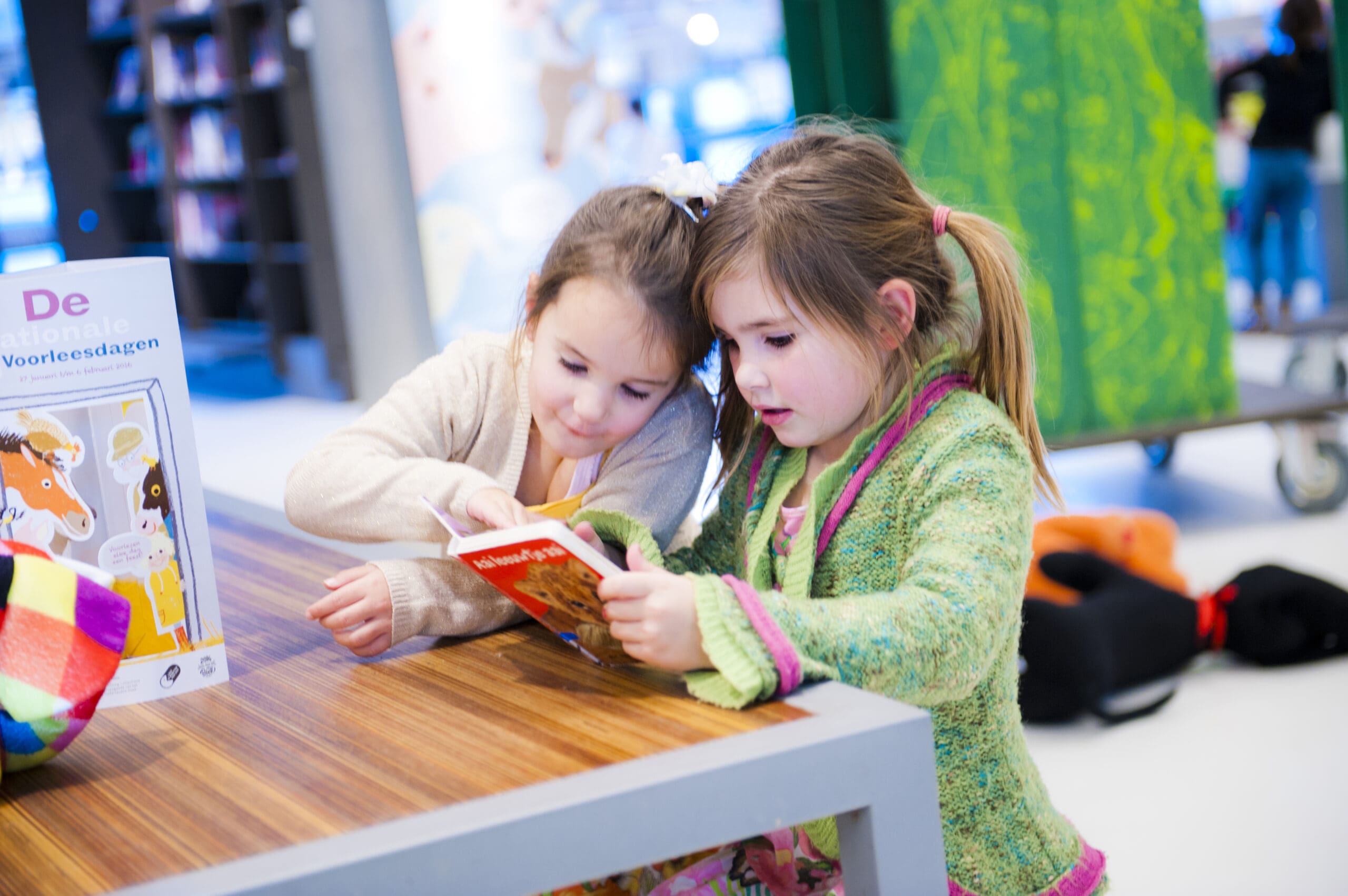 twee kindjes aan een tafel die samen een boek lezen