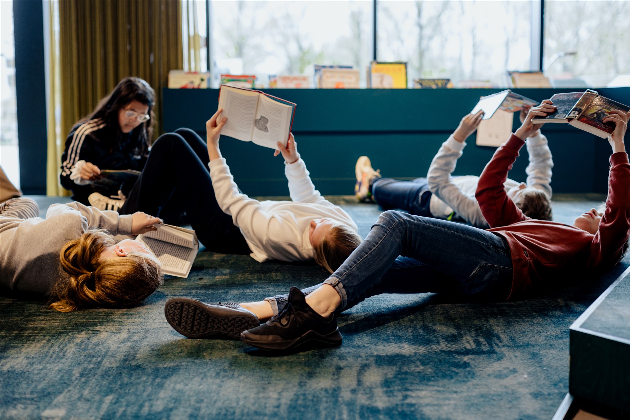 kinderen lezen boeken op de vloer van een bibliotheek