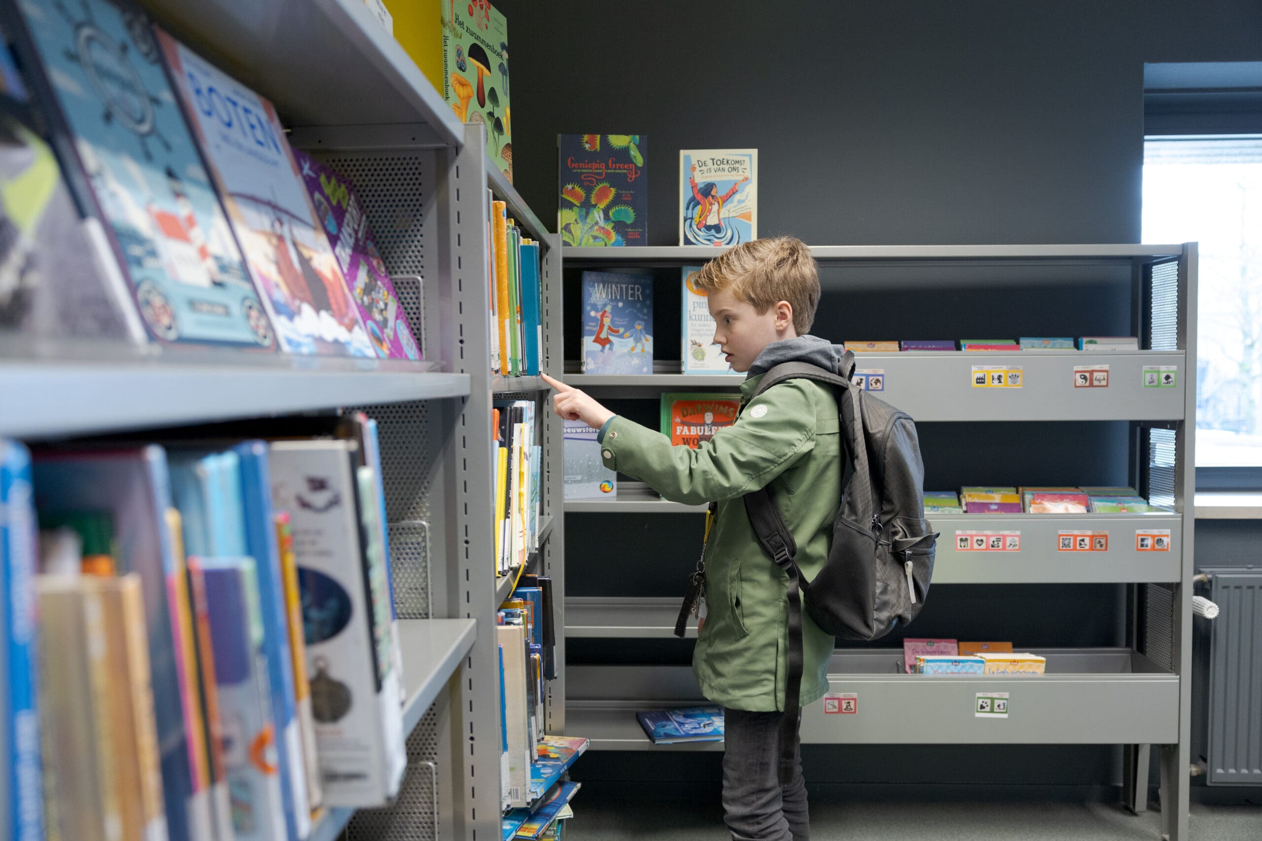 Een jongen zoekt een boek in de bibliotheek
